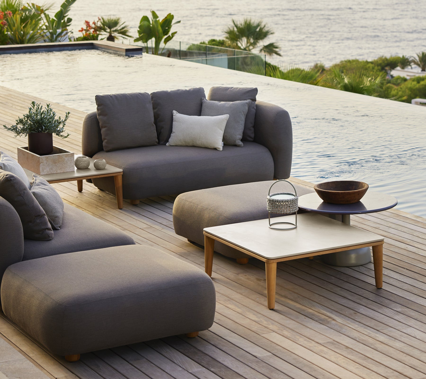 Moderne loungesets voor buiten met grijze bank, stoel en houten salontafel.
