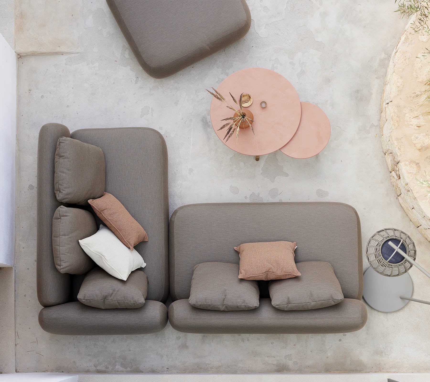 Een stijlvolle zitarrangement met een neutraal gekleurde bank met decoratieve kussens, vergezeld van een uniek twist-koffietafel.