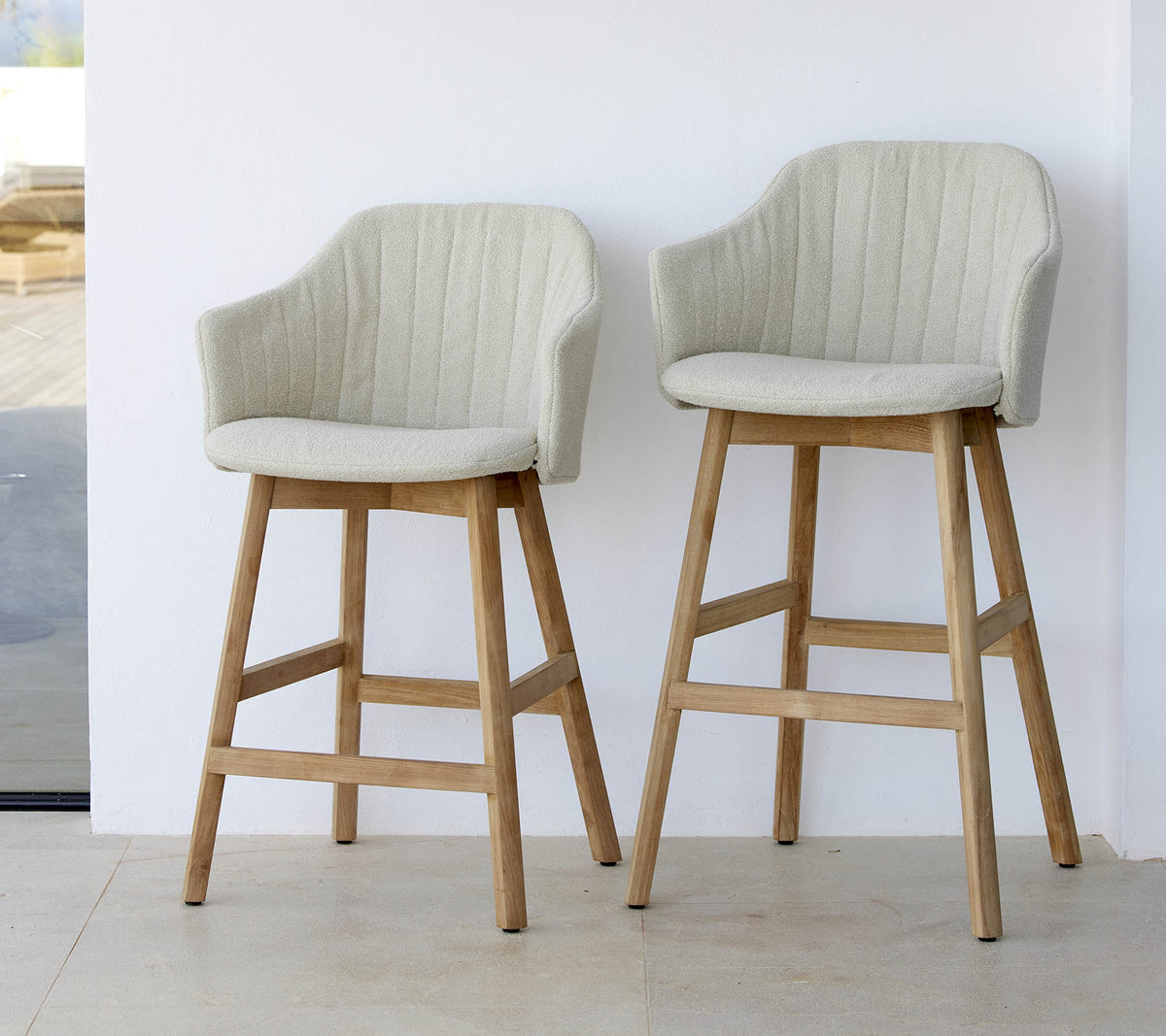 Twee stijlvolle, lichtgekleurde stoelen met gebogen rugleuning en houten poten, die een modern en comfortabel ontwerp laten zien.