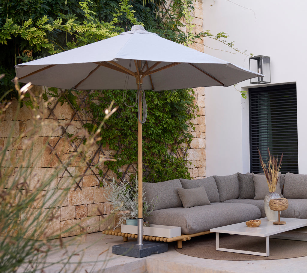 Moderne loungegebied met een grijze sofa, witte tafel en grijze parasol.