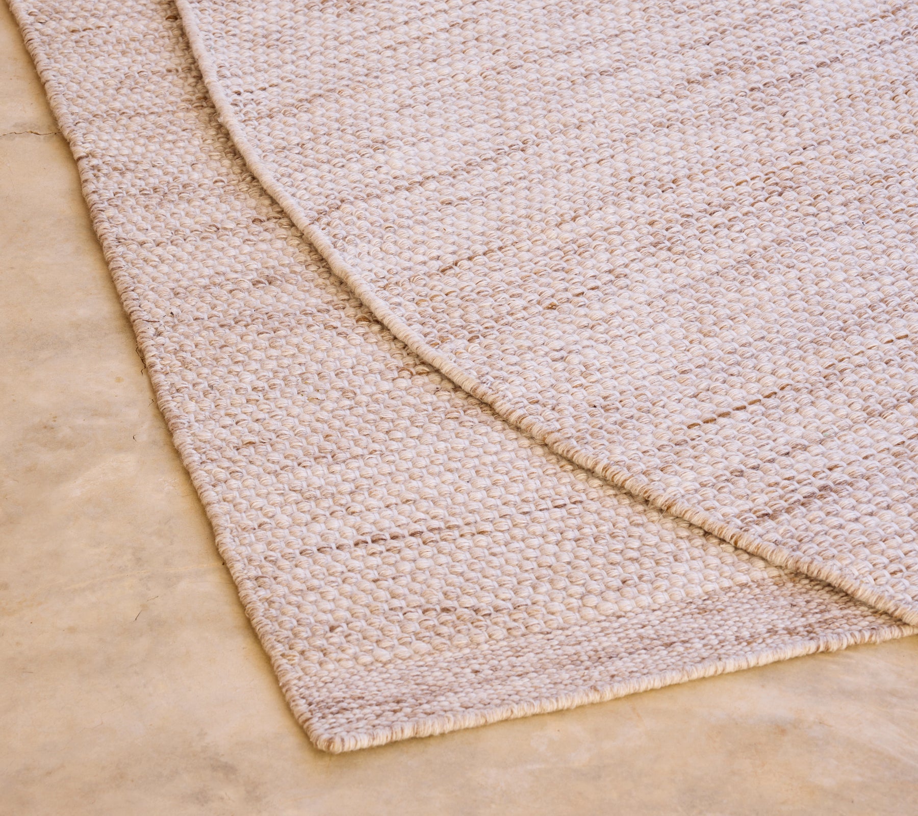 Beige tapijt met een textuurpatroon op een lichtgekleurde vloer.