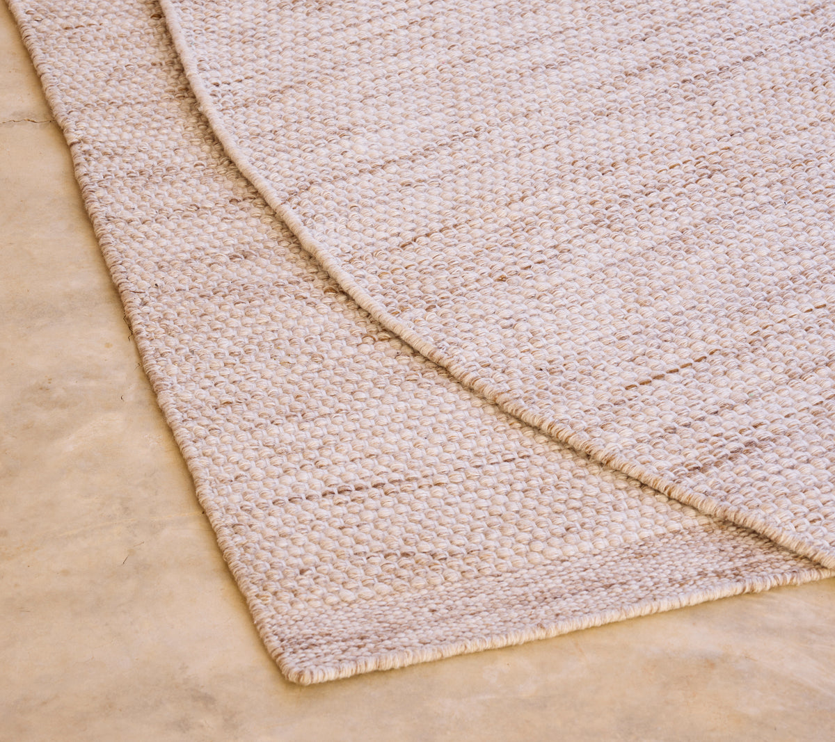 Beige tapijt met een textuurpatroon op een lichtgekleurde vloer.