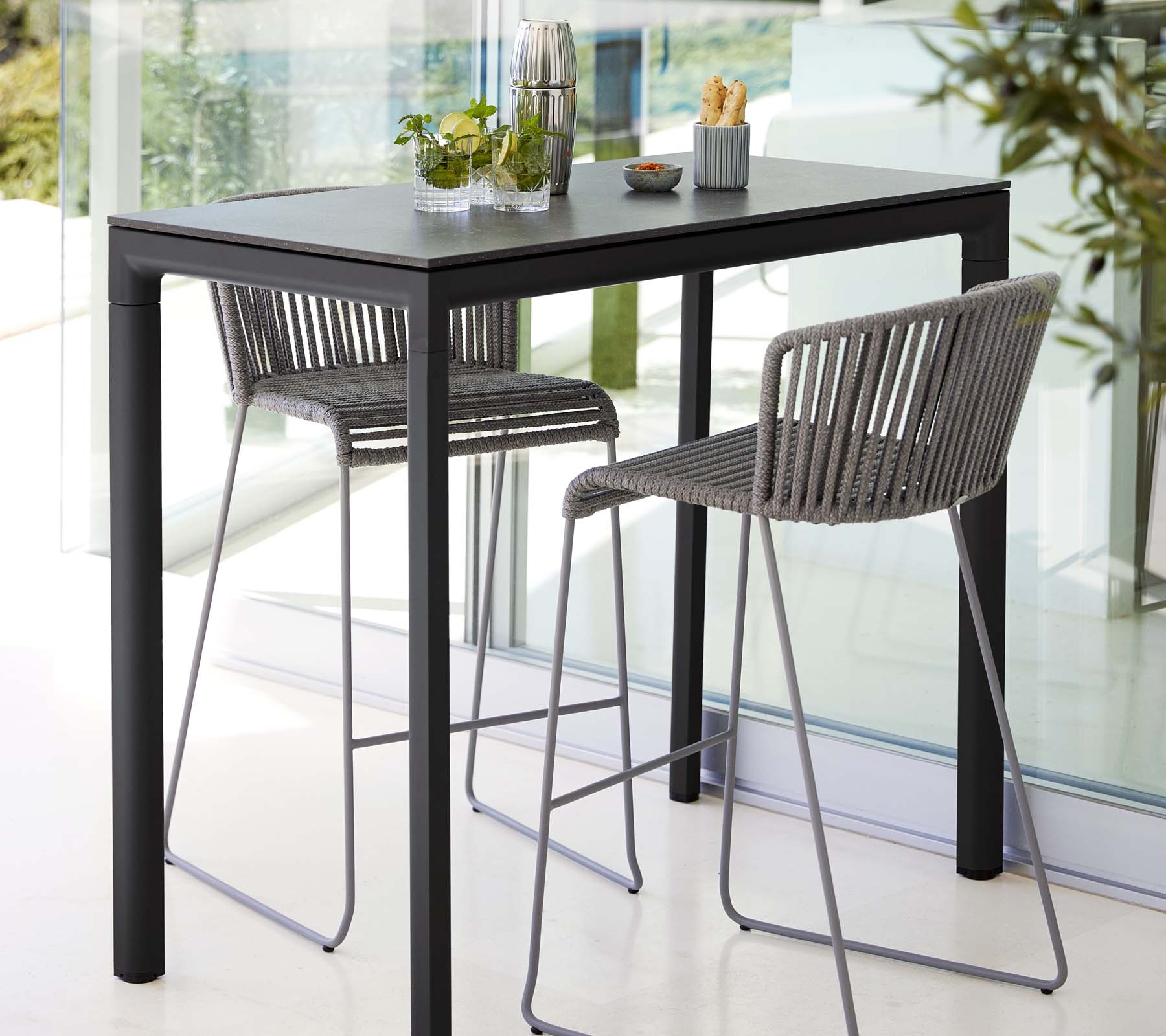 Modern tafel met twee stijlvolle krukken, met een strak ontwerp, in combinatie met decoratieve planten en minimalistische eetaccessoires.