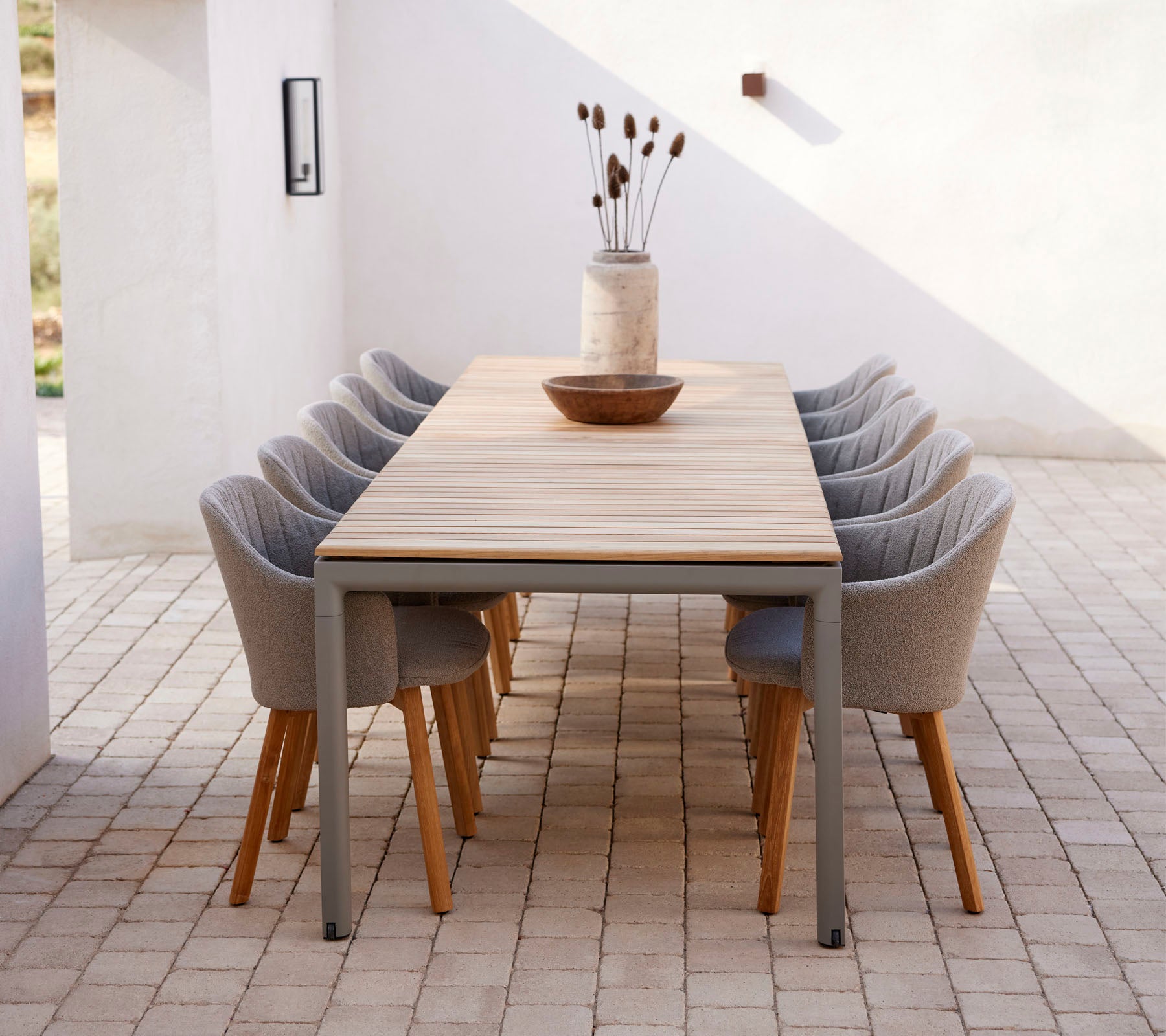 Een lange tafel met moderne stoelen, gestyled met een decoratieve vaas en kom, waardoor een uitnodigende ruimte voor bijeenkomsten ontstaat.