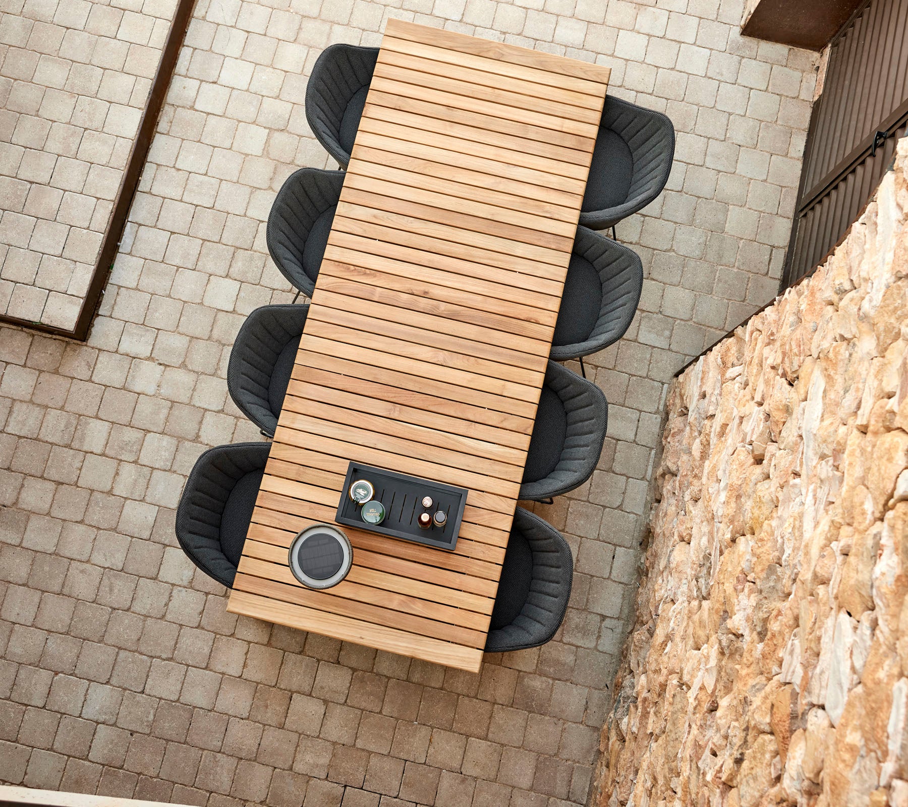 Een lange houten tafel met een strak ontwerp, omringd door vier moderne stoelen, met een decoratief middenstuk.