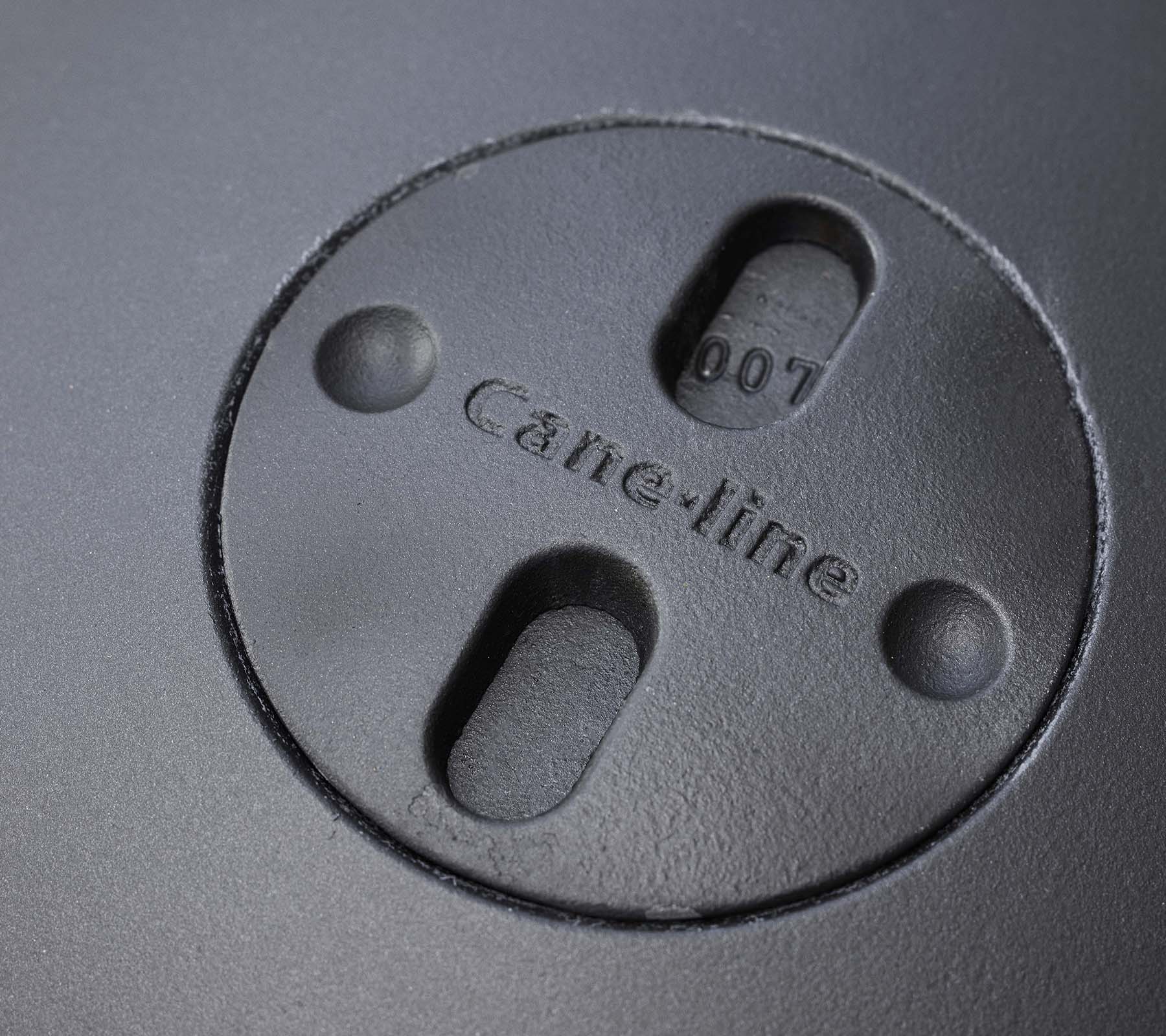 Close-up van een circulair kenmerk met ingegraveerd "Cane-line" logo en twee sleuven, onderdeel van een vuurkorfontwerp.