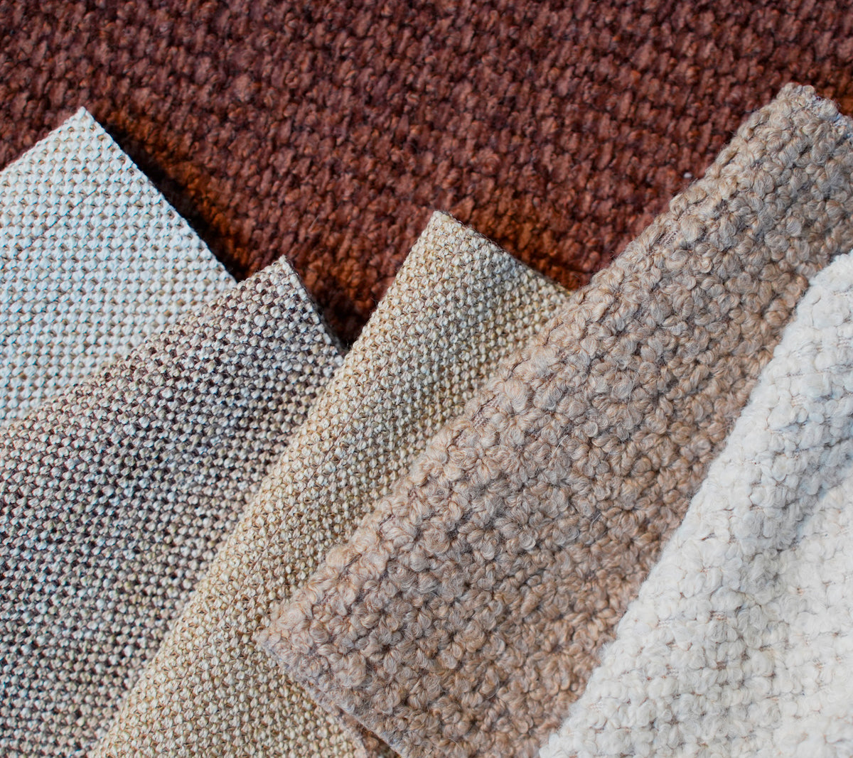 Stalen van verschillende textuurstoffen in bruin, beige, lichtgrijs en wit.
