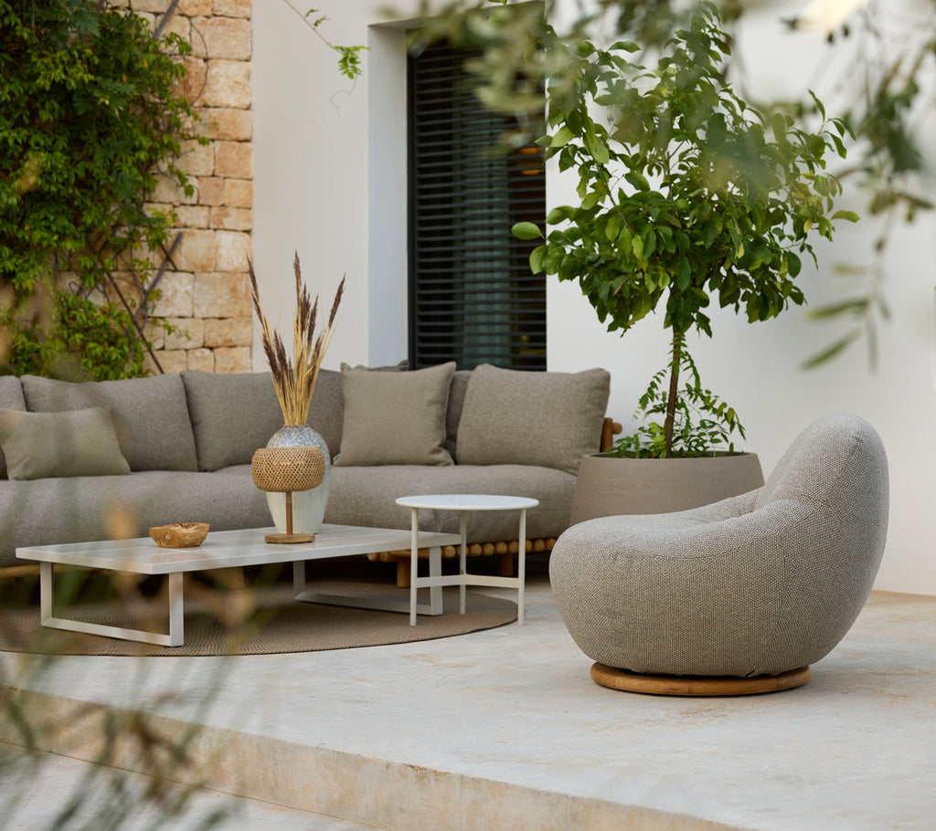 Moderne loungegebied met een grijze hoekbank, een witte salontafel en een ronde stoel.