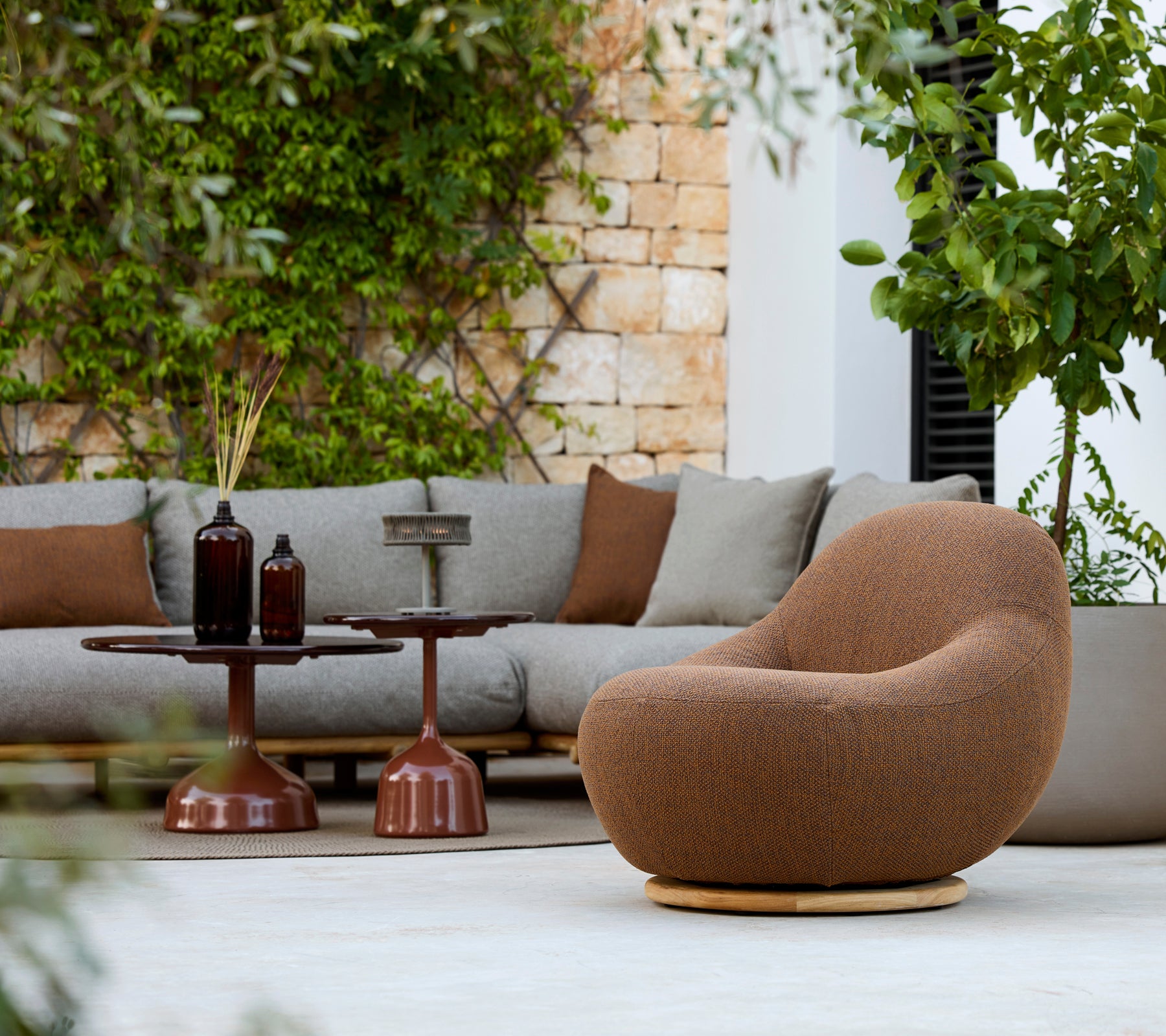 Moderne loungegebied met een bruine fauteuil, grijze bank en een bruine salontafel.