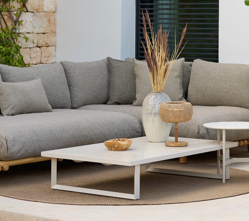 Moderne loungegebied met een grijze bank en een witte salontafel met decoratie.