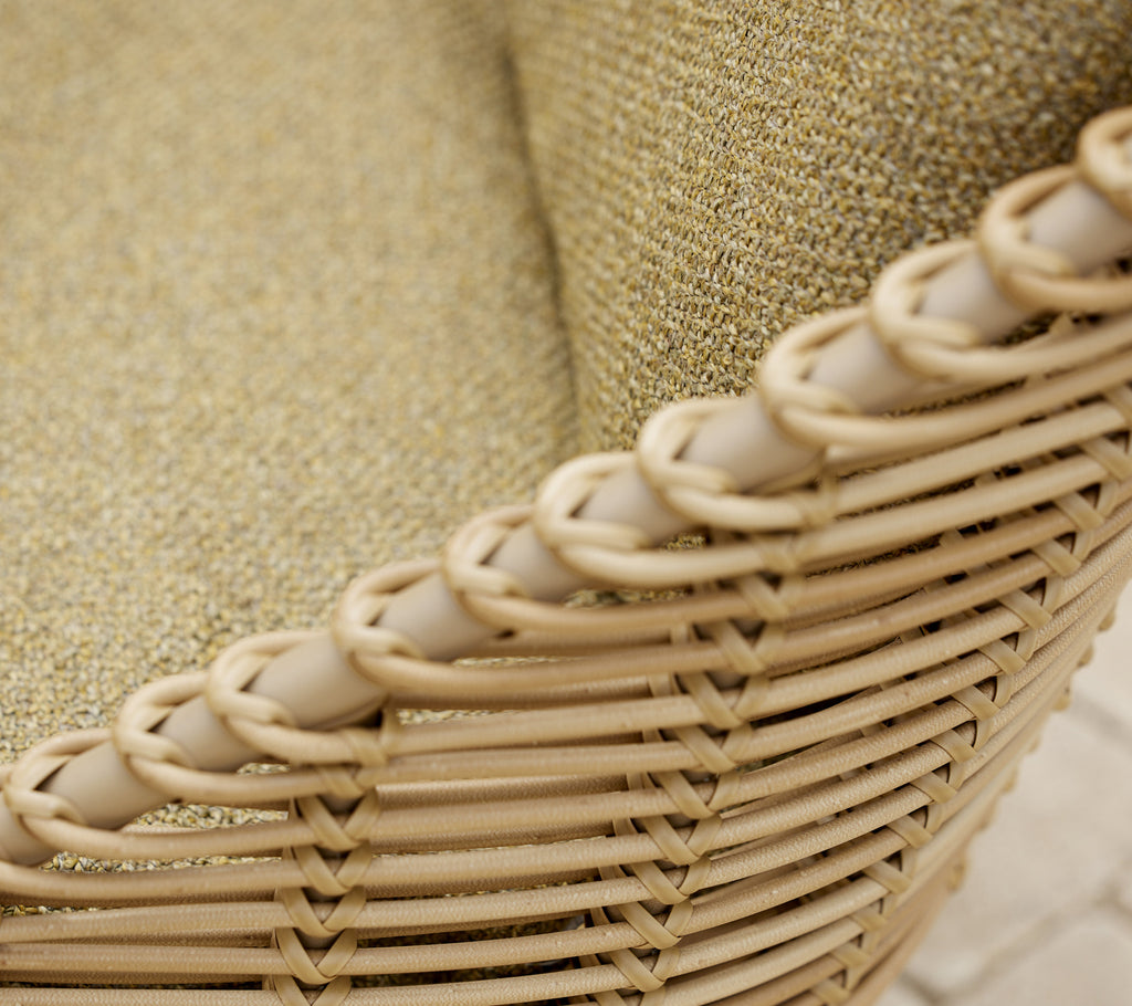 Close-up van de Hive loungechair, die zijn geweven ontwerp en textuurstof in een natuurlijke kleur toont.