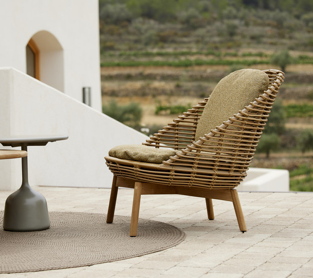 Hive loungechair met comfortabele opsteunpufs, elegant ontworpen met geweven elementen en een natuurlijke houten afwerking.