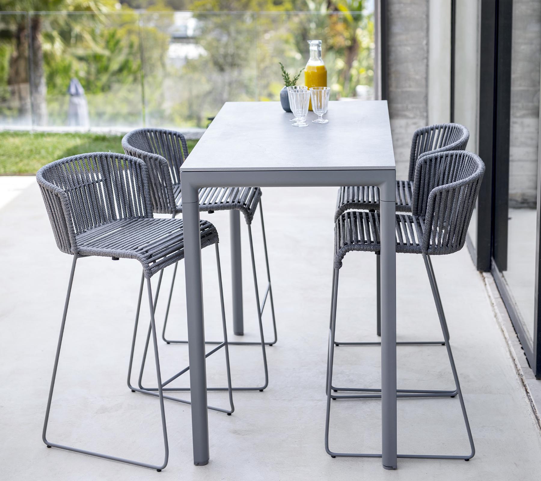 Moderne eettafelset met een strak tafel en vier hoge stoelen met een minimalistisch ontwerp, ideaal voor informele bijeenkomsten.