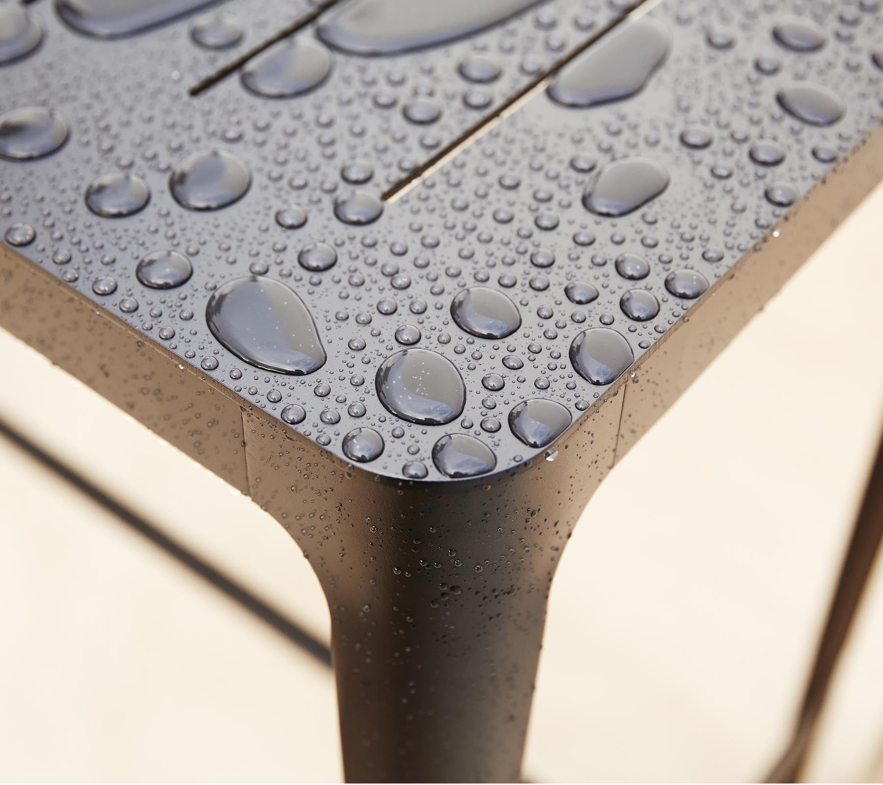 Close-up van een gestructureerd oppervlak met waterdruppels, dat het slanke ontwerp en de details van het materiaal benadrukt.