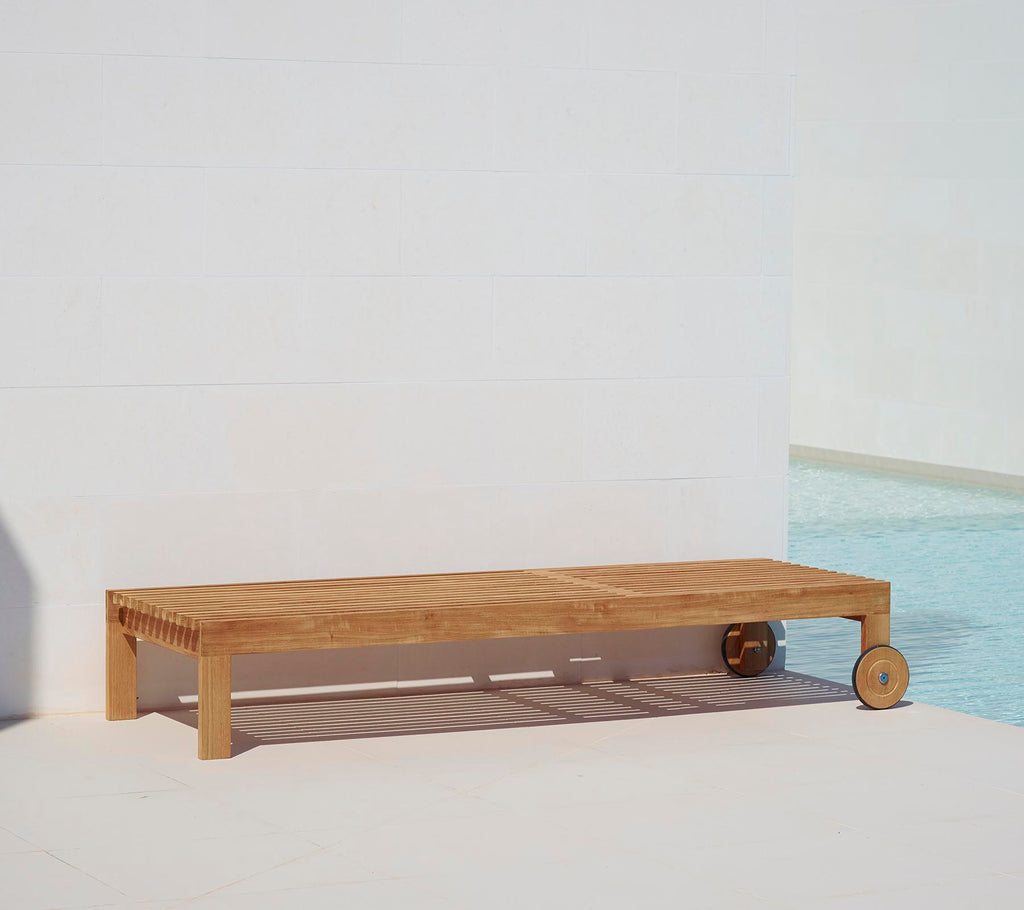 Houten ligbed met een minimalistisch ontwerp, voorzien van een glad oppervlak en een wiel voor gemakkelijke mobiliteit. Ideaal voor ontspanning bij het zwembad.