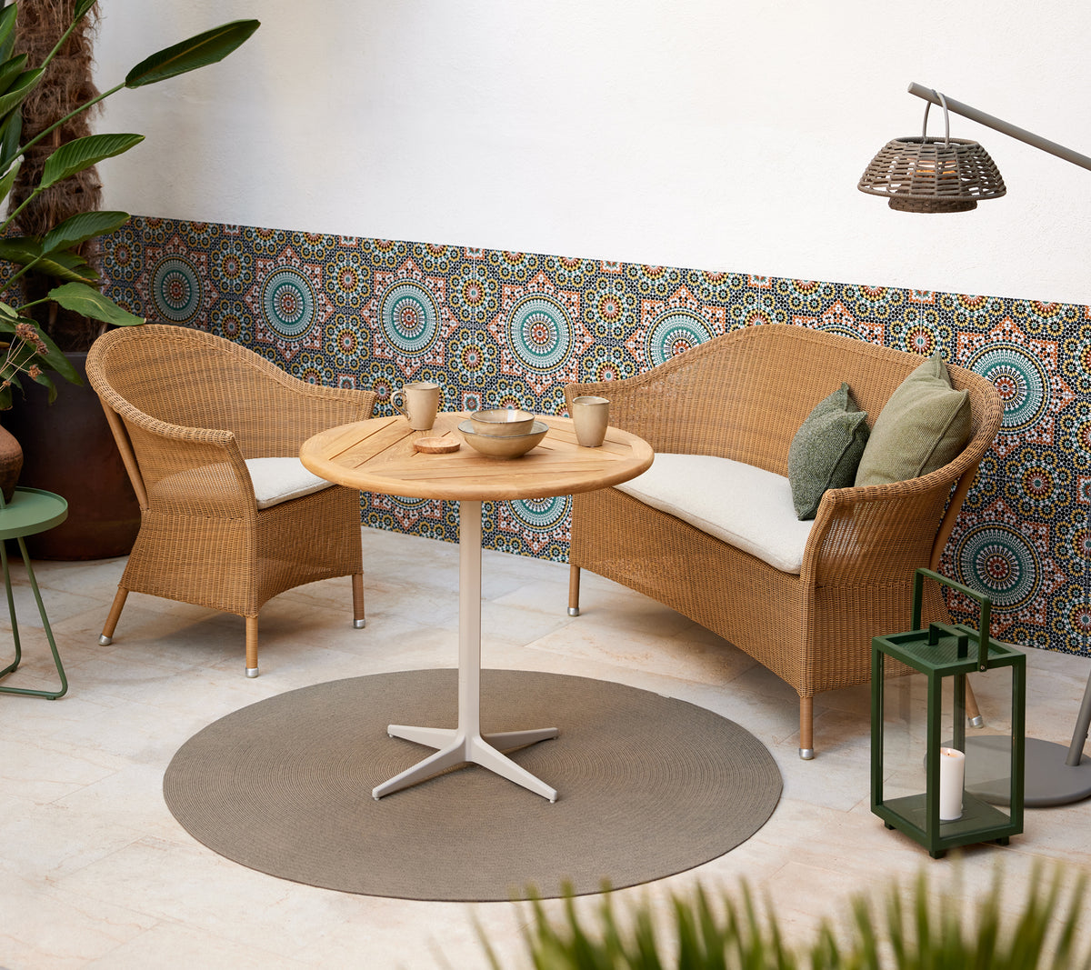 Een gezellige zithoek met gevlochten stoelen en een ronde tafel, aangevuld met levendige cirkelpatronen op de achtergrond.