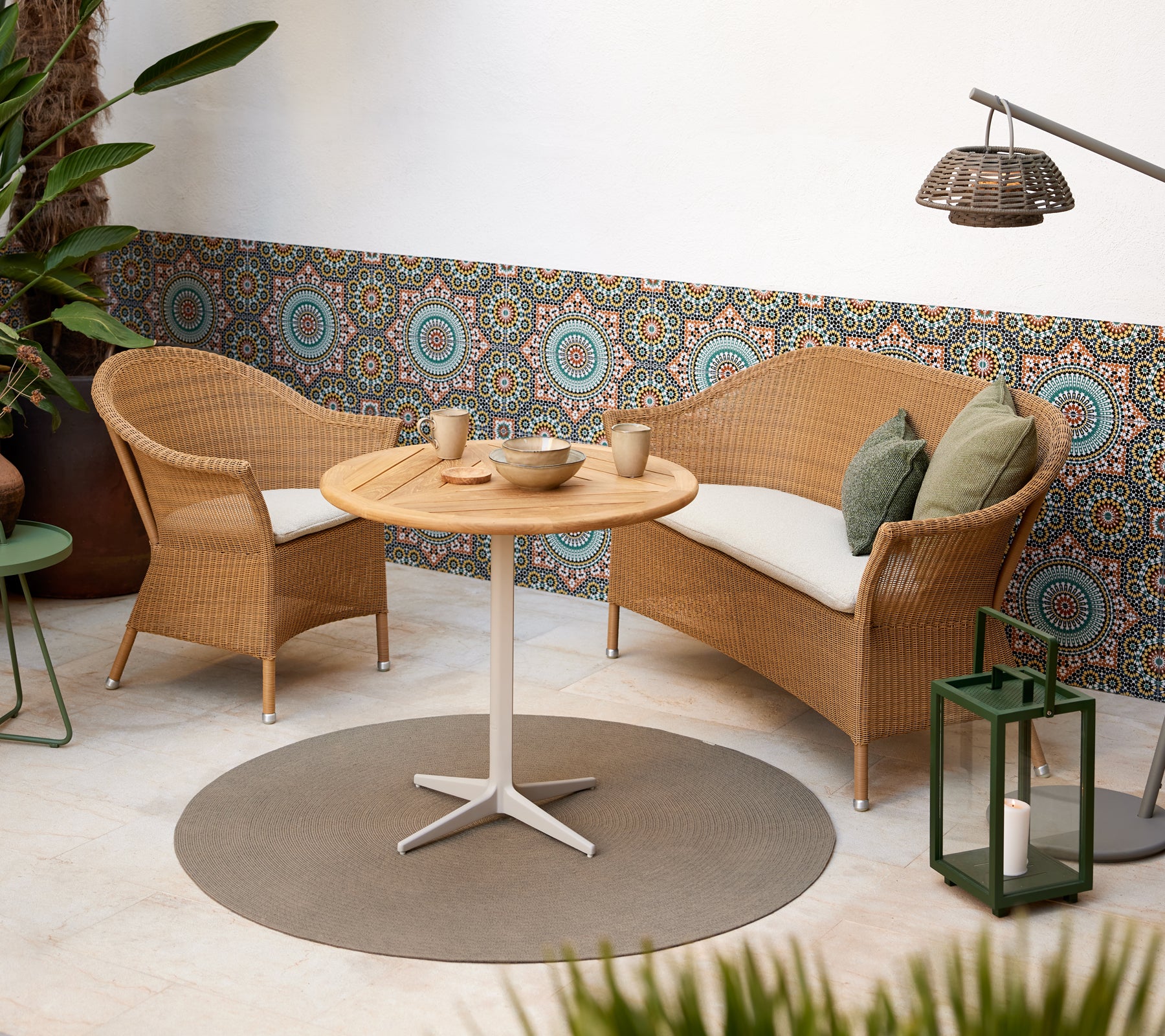 Een gezellige zithoek met gevlochten stoelen en een ronde tafel, aangevuld met levendige cirkelpatronen op de achtergrond.