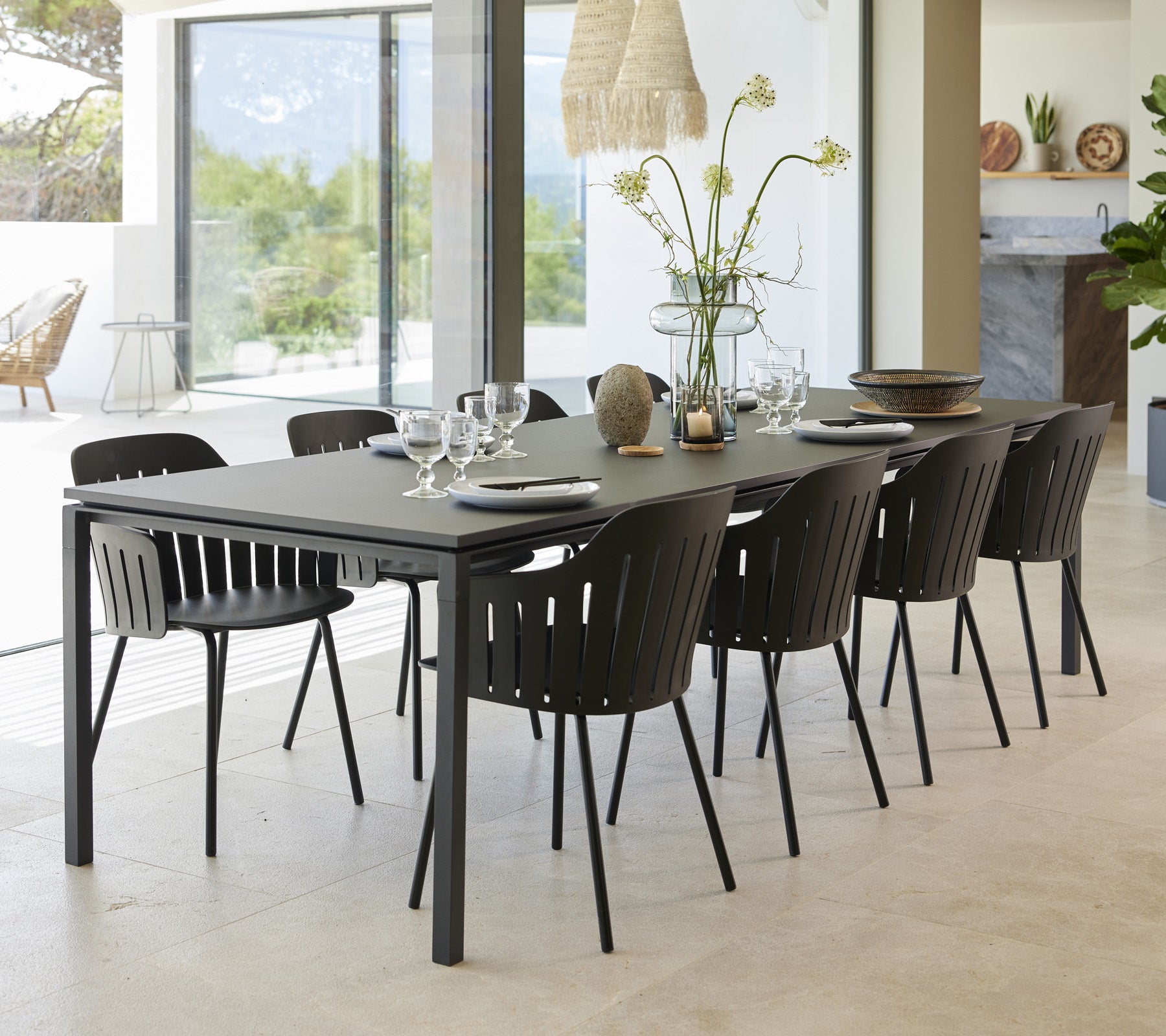 Een stijlvolle eettafelset met acht zwarte stoelen, elegant gerangschikt met servies en een vaas met bloemen als middelpunt.