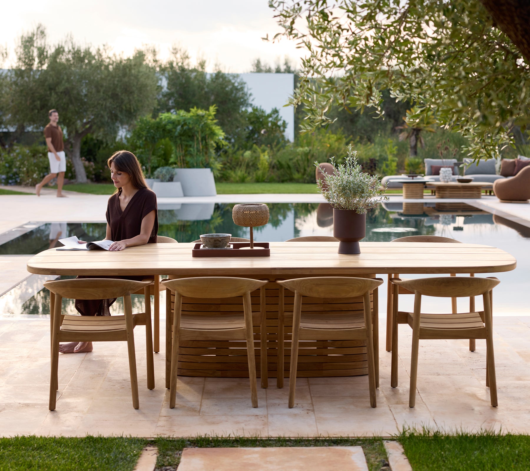 Moderne buitenmeubilair met stoelen naast een zwembad omgeven door groen.