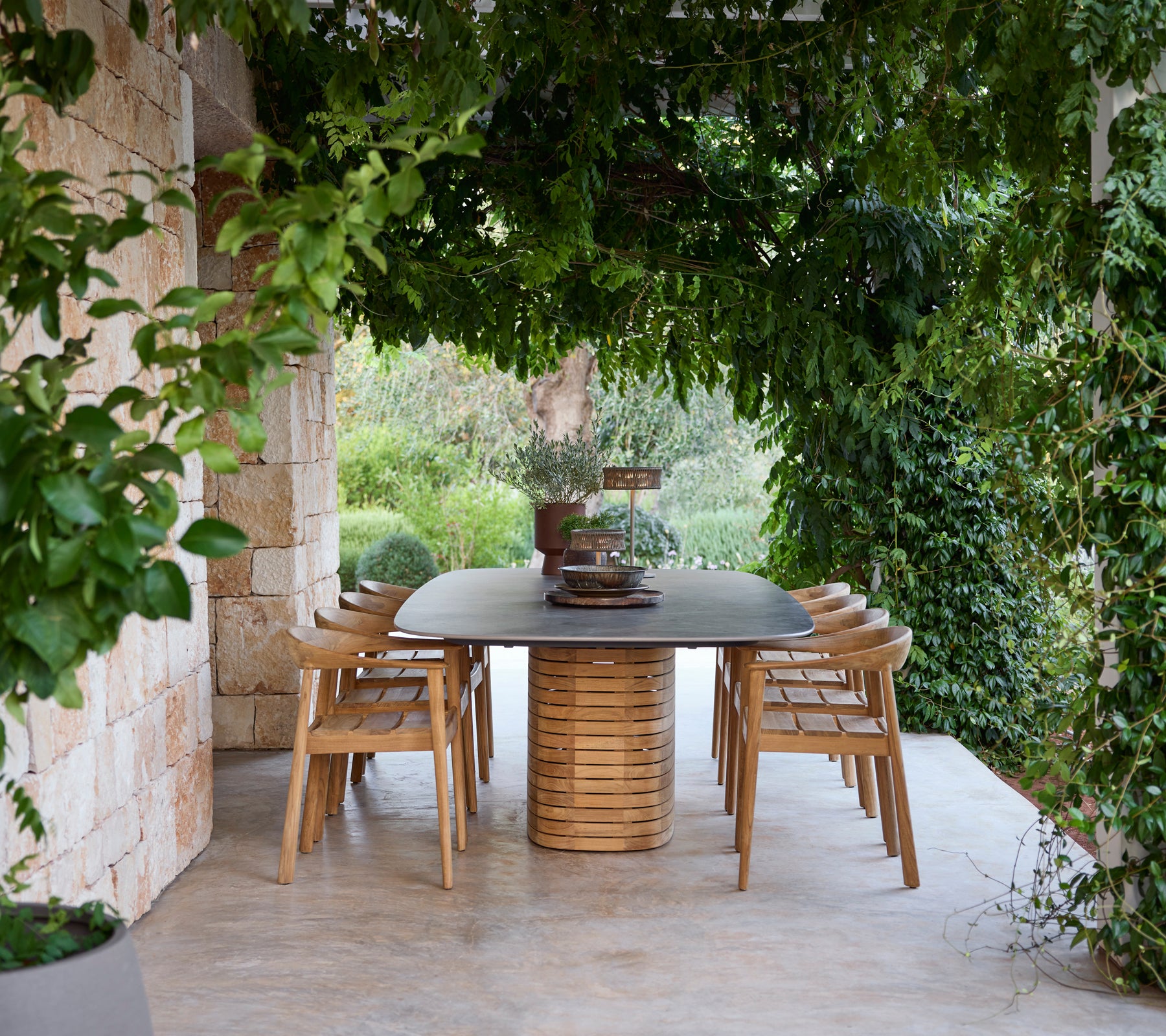 Houten eettafel omringd door stoelen onder groen.