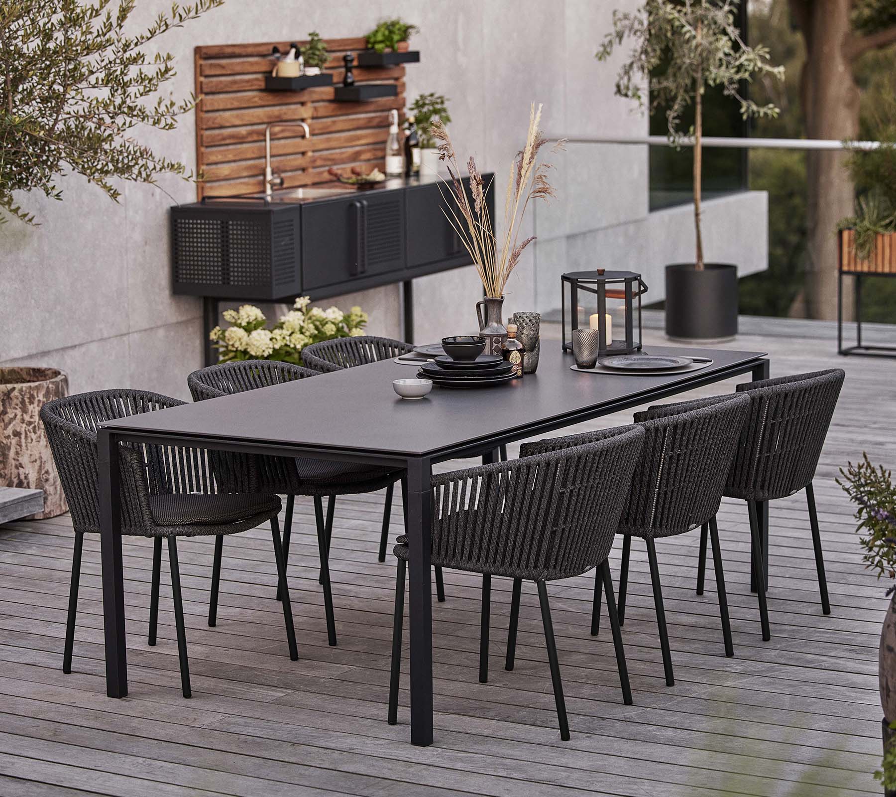 Een slank zwart tafel met zes Moments-stoelen, met servies en decoratieve elementen voor een aantrekkelijke dinerervaring.