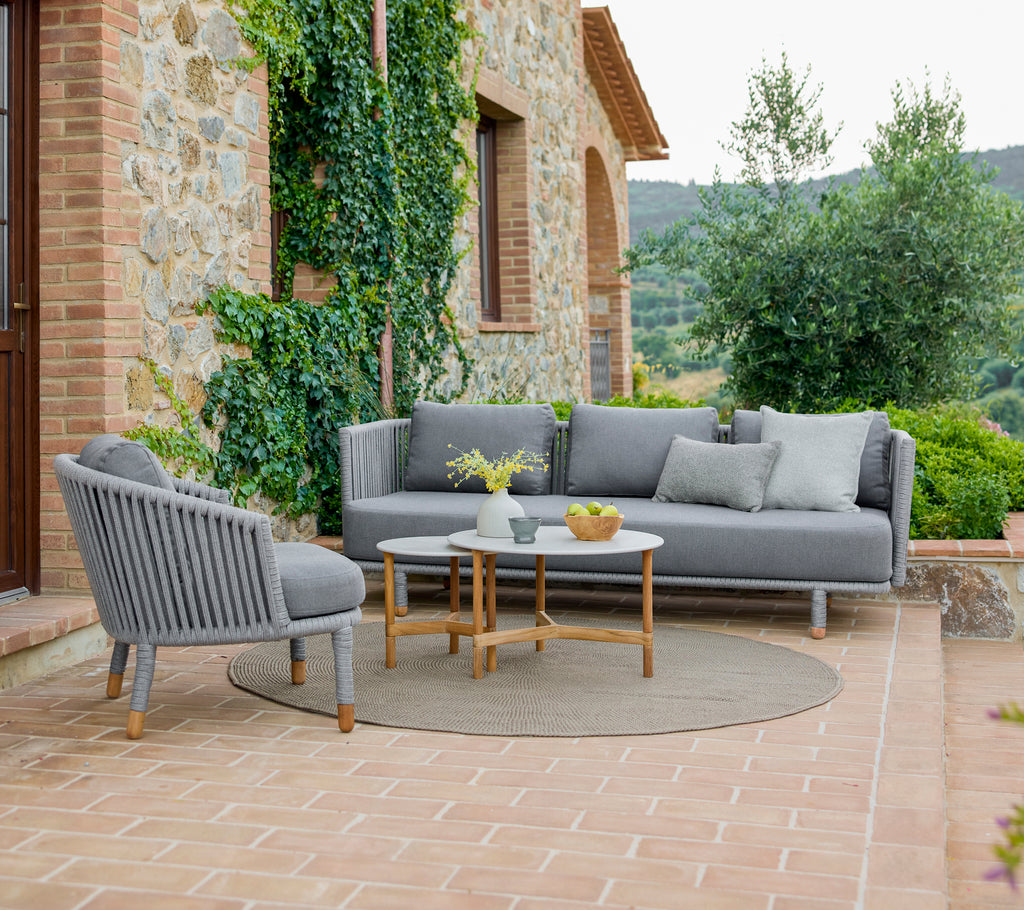 Stijlvolle loungechair en sofa met een gezellige opstelling, vergezeld van elegante salontafels, omringd door groen.