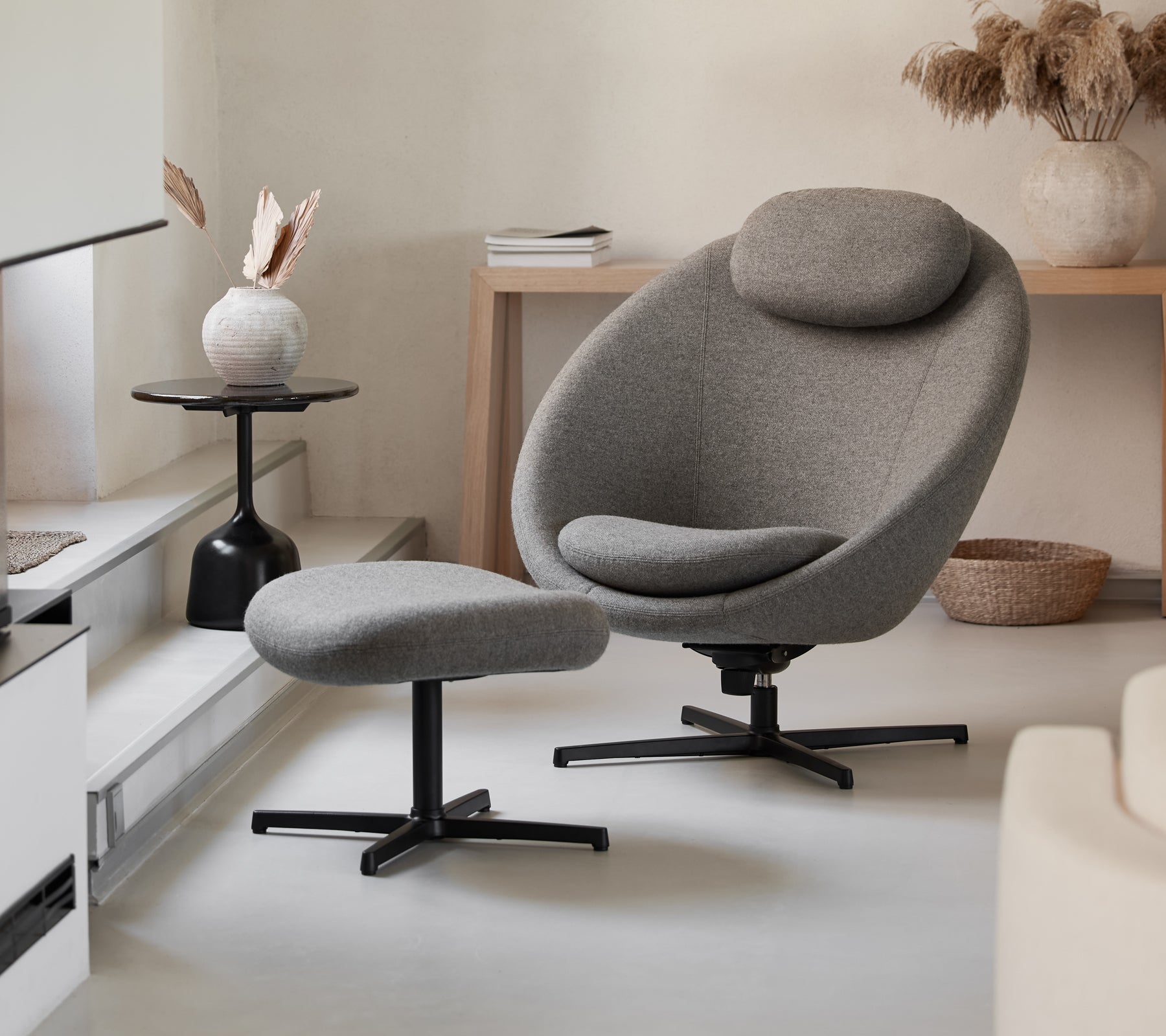 Stijlvolle grijze stoel met bijpassende ottoman, met een slank ontwerp en comfortabele rondingen, aangevuld met moderne decor elementen.