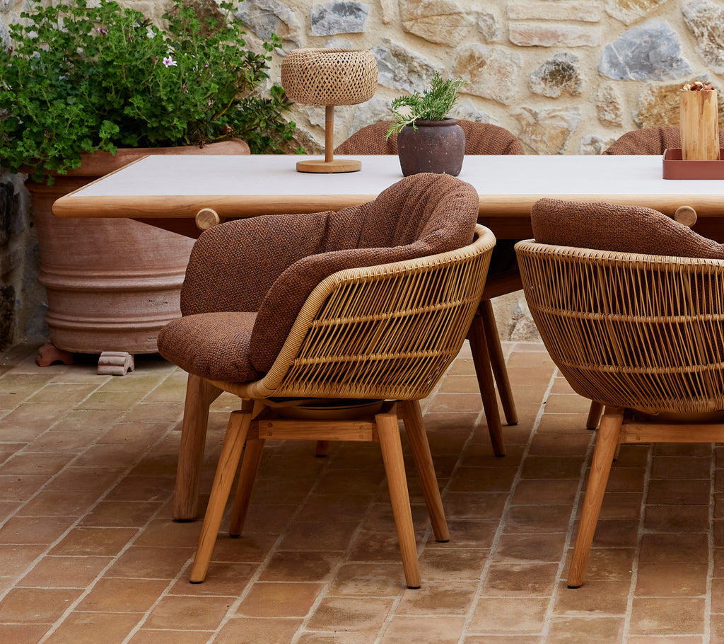 Elegant dining setup featuring swivel chairs with teak legs around a stylish table, complemented by decorative plants and accessories.