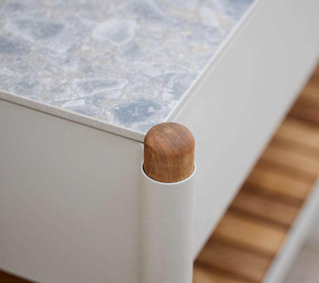 Houten hoekaandacht van een meubel met een gestructureerd oppervlak en verticale ondersteunen, wat een moderne esthetiek benadrukt.