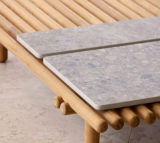 Een houten platform heeft twee stenen tafelbladen, waarmee een modern ontwerp met natuurlijke elementen voor een stijlvolle presentatie wordt benadrukt.