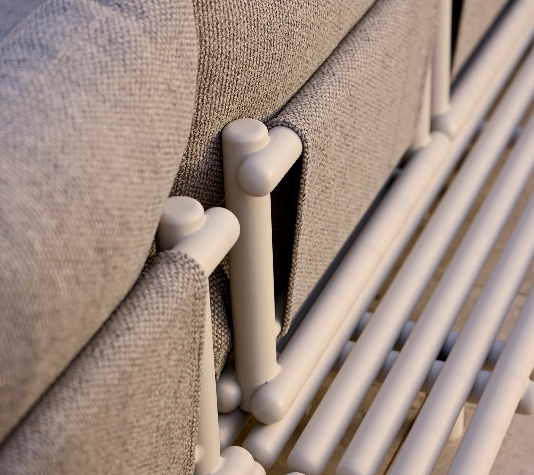 Close-up van een loungeplatform met aluminium staven en een gestructureerde grijze stof, die moderne designelementen benadrukt.