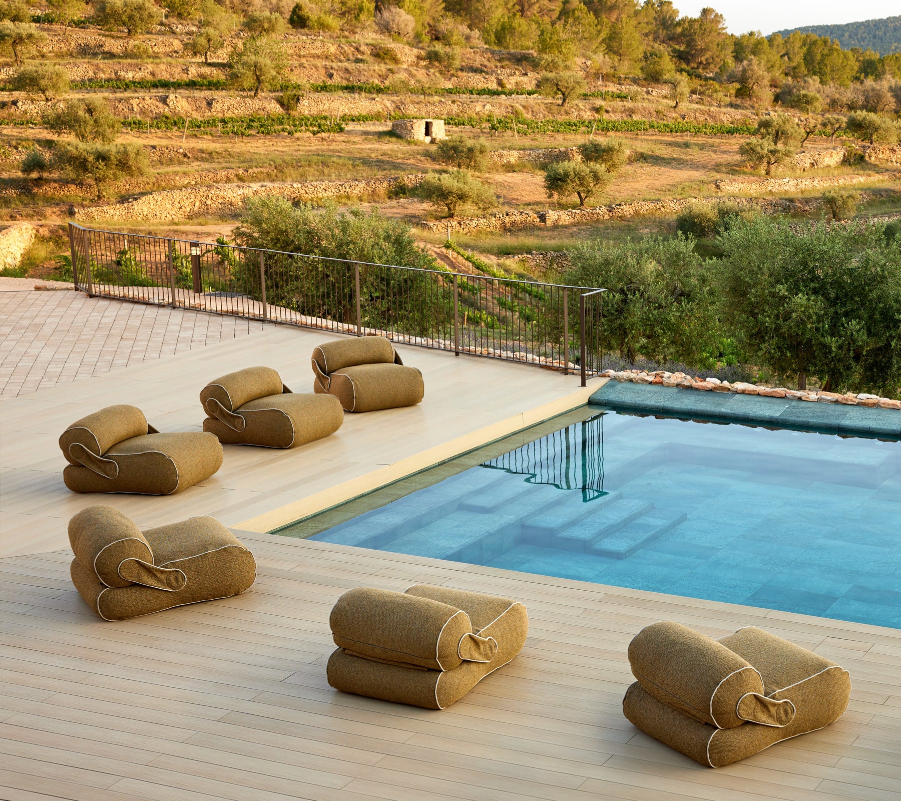 Een serene omgeving met comfortabele loungezittingen dichtbij een rustige pool, omgeven door weelderig groen en een schilderachtig landschap.