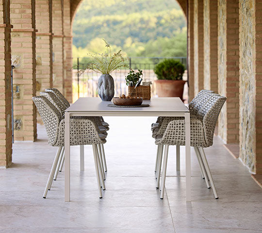 Een stijlvolle eetopstelling met Vibe eetstoelen en een Pure eettafel in een zachte zandkleur, met decoratieve elementen.