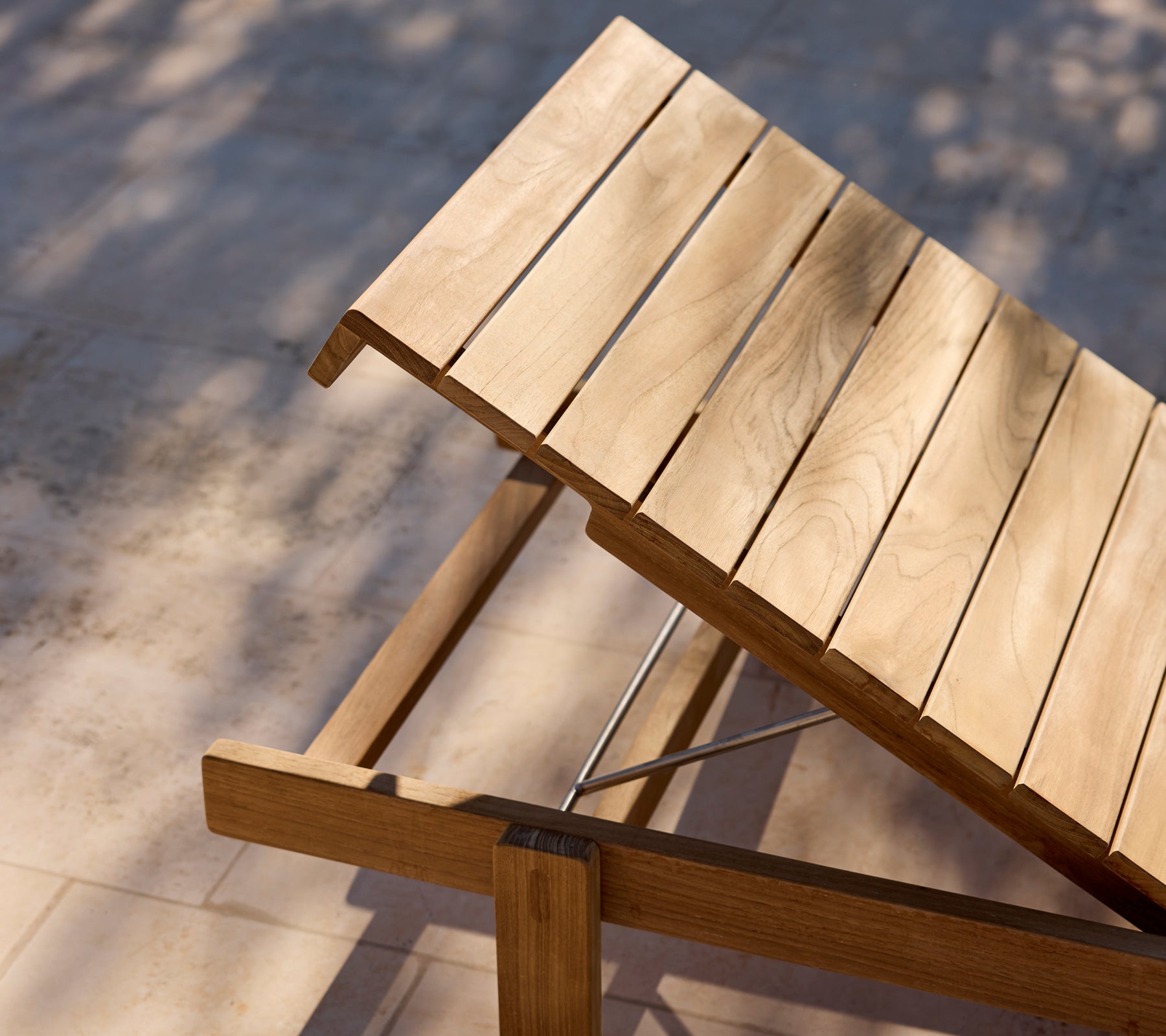 Moderne houten lounge stoel met verstelbare rugleuning op een zonnig terras.