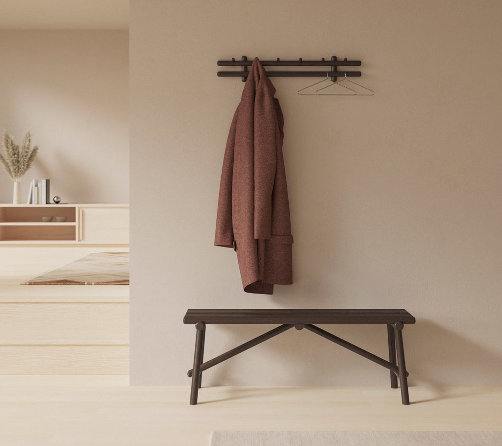 Een minimalistische inrichting met een houten bank en een jas die aan een wandbevestigde rek hangt, waarmee de eenvoud en functionaliteit van de ruimte wordt verbeterd.