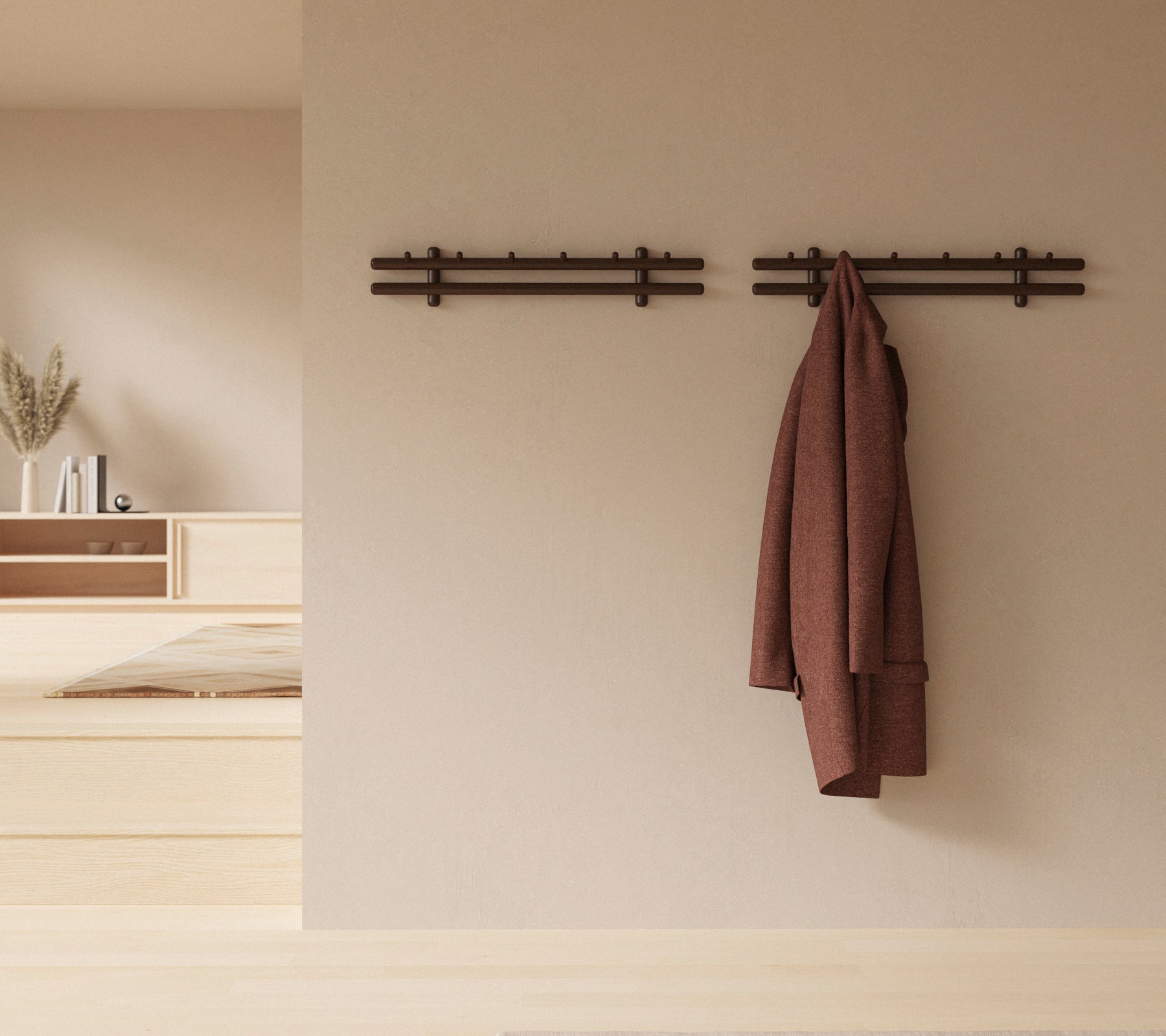 Een minimalistische wanddisplay met houten stokken die een jas en een verzameling lappen vasthouden, waardoor de rustieke decoratieve esthetiek wordt versterkt.