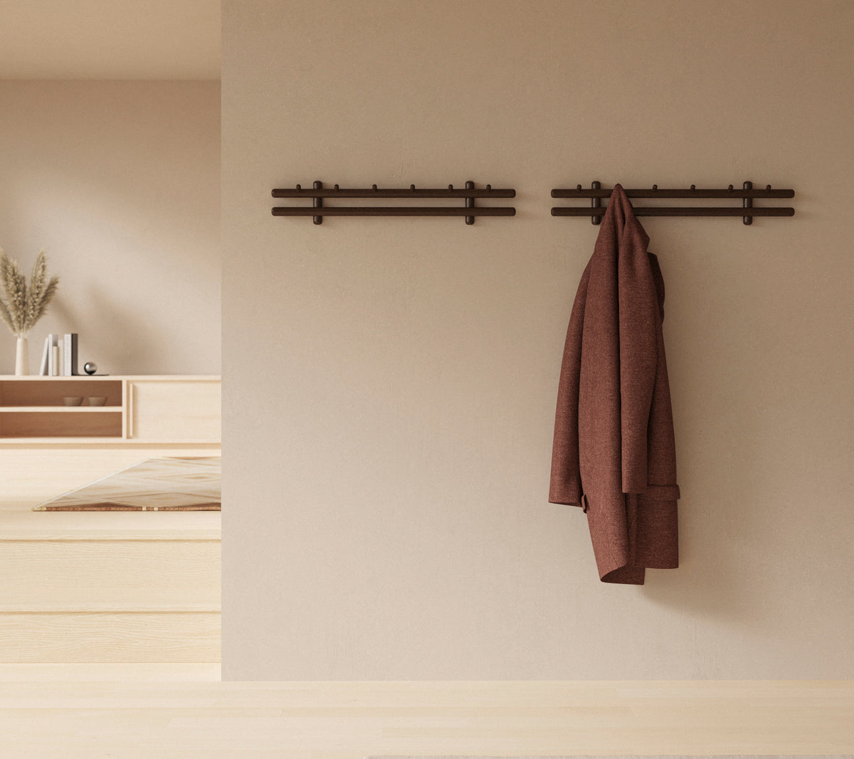 Een minimalistische wanddisplay met houten stokken die een jas en een verzameling lappen vasthouden, waardoor de rustieke decoratieve esthetiek wordt versterkt.