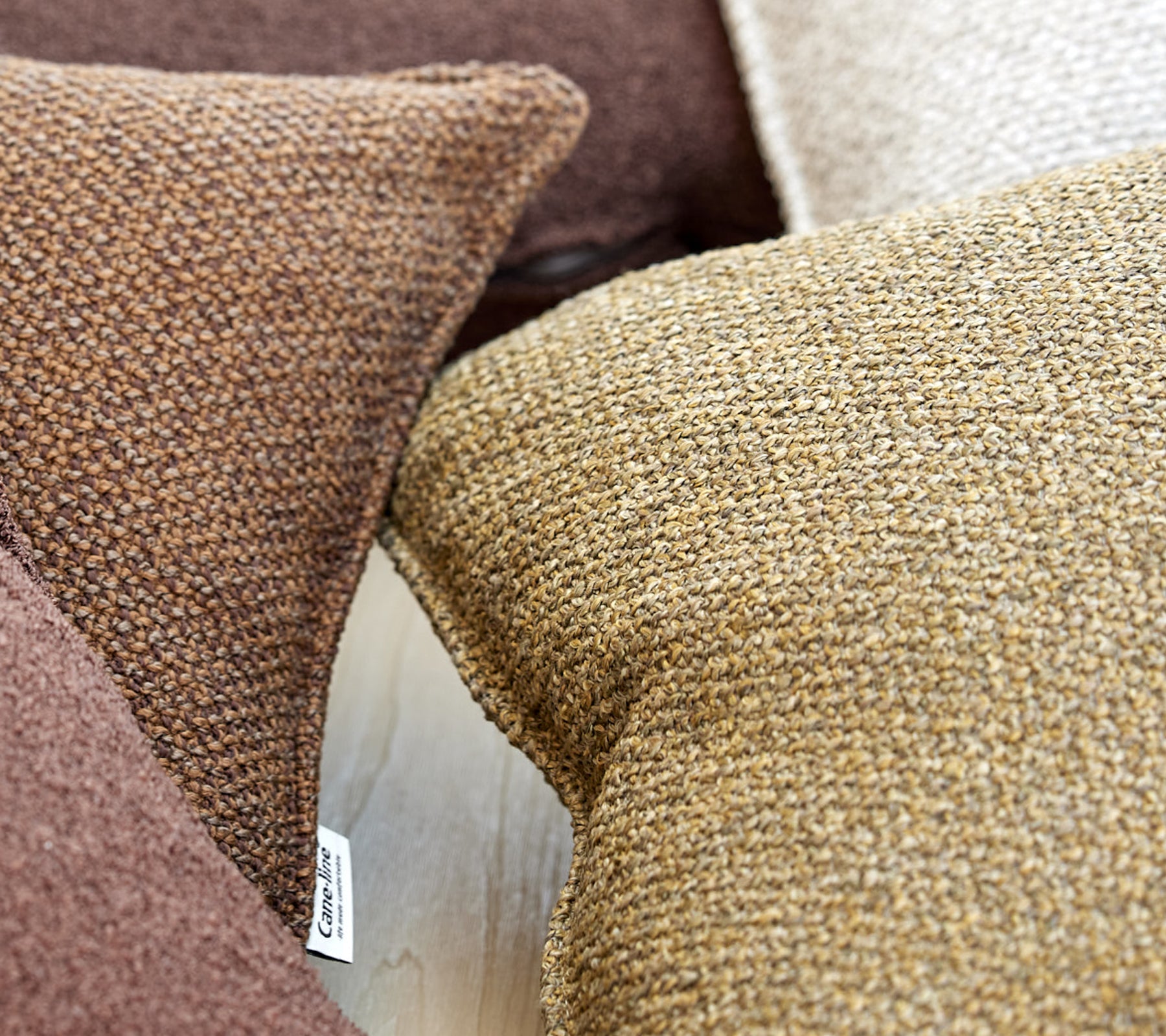 Een close-up van textured kussens in verschillende bruintinten, die warmte en comfort aan de omgeving toevoegen.