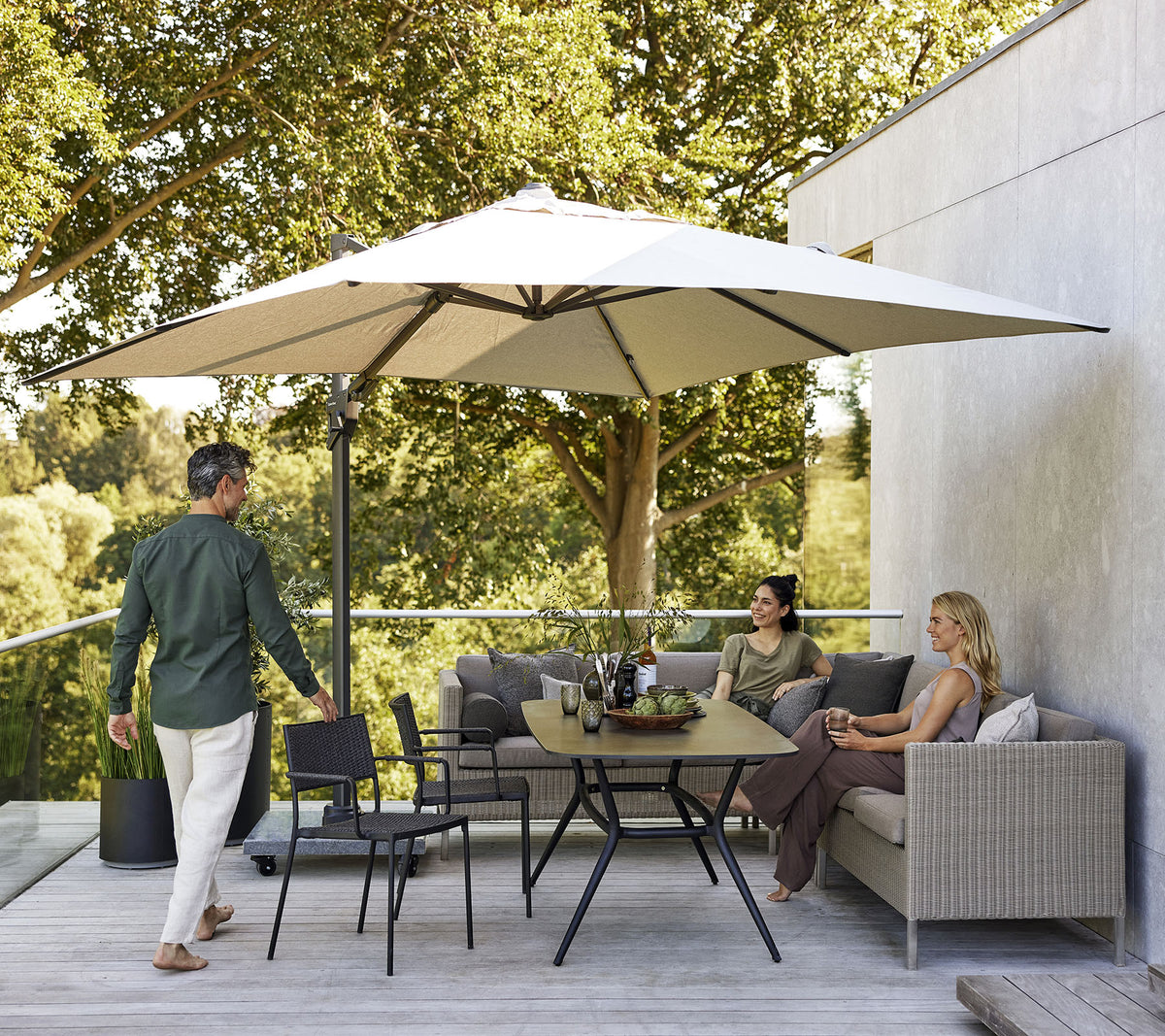 Een stijlvol zitgedeelte met een grote parasol, met een bank, stoelen en een eettafel omringd door weelderig groen.